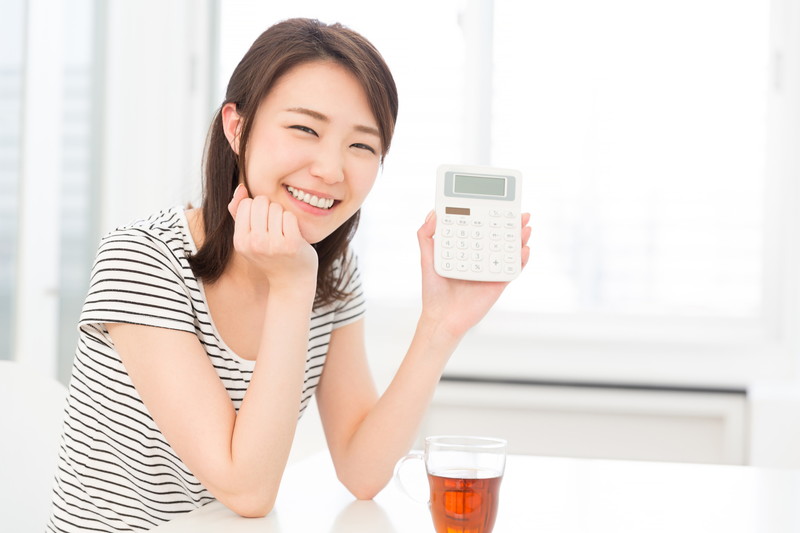 笑顔で電卓を持つ、若い日本人女性