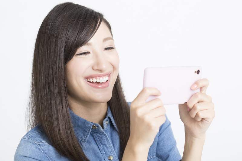 スマートフォンの画面を笑顔で見る女性